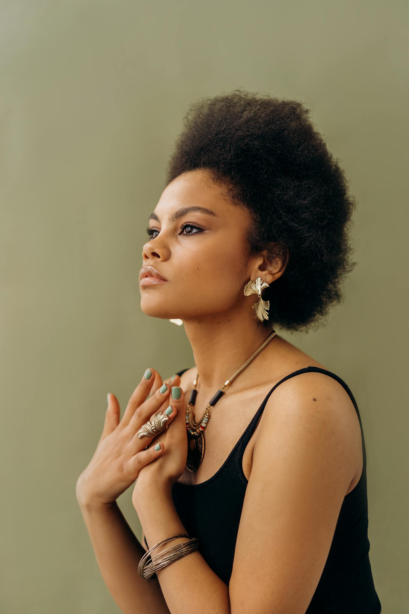 A graceful woman with an afro hairstyle and jewelry, exuding elegance and concentration.