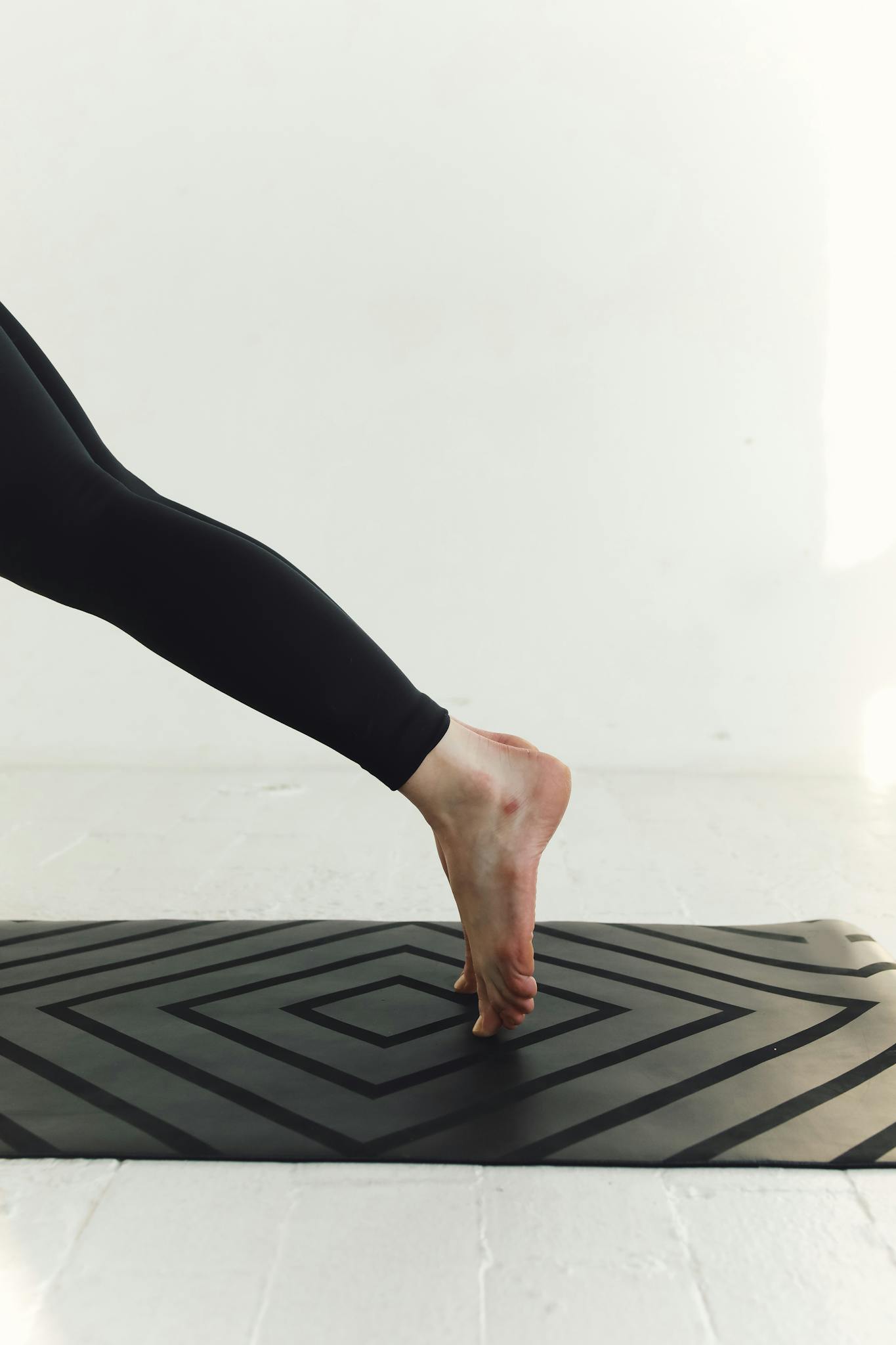 Person practicing yoga pose on a stylish mat, focusing on balance and elegance.